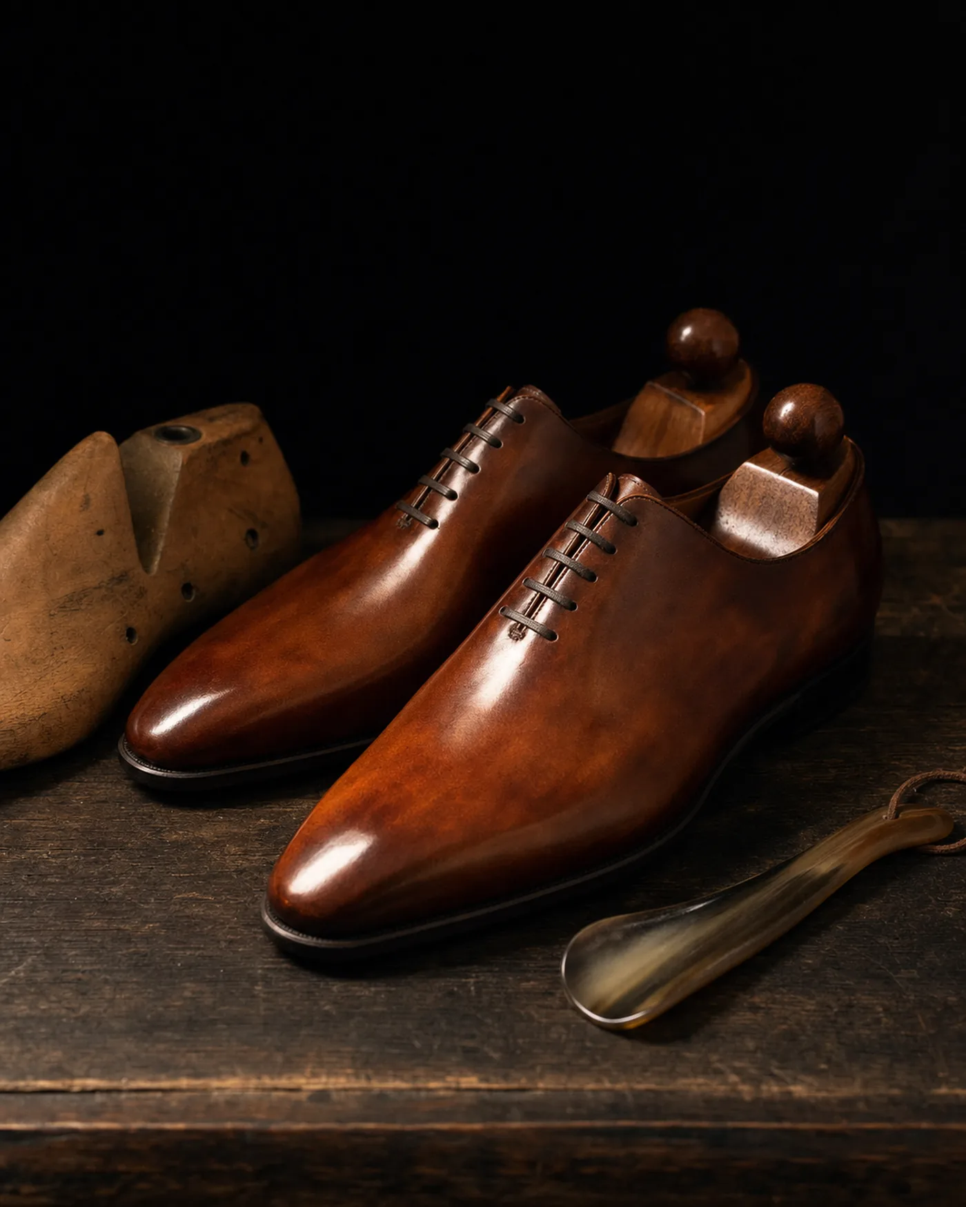 Cognac whole-cut oxfords beside a wooden shoe last.
